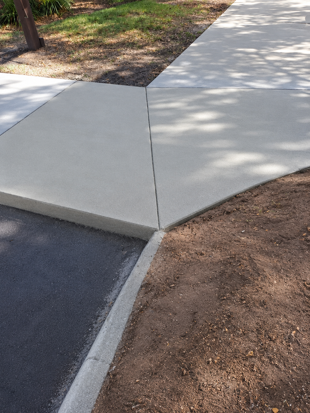 Fresh concrete sidewalk meeting asphalt driveway with clean edge detail